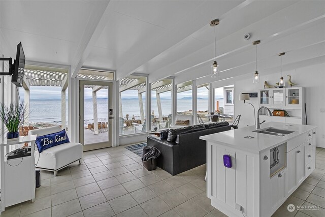 living room with sink, a water view, and light tile patterned floors