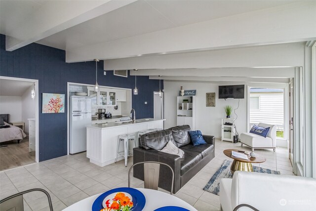 living room featuring beam ceiling, sink, and light tile patterned flooring