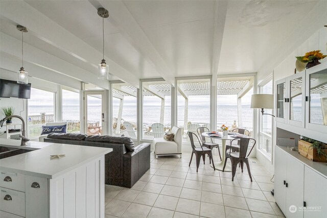 sunroom / solarium with a water view, a healthy amount of sunlight, and sink