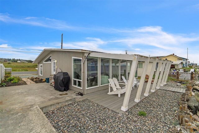 back of house with a sunroom, a deck, and a patio