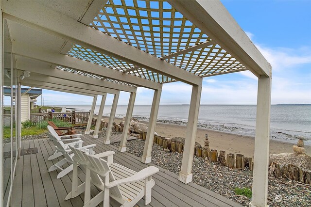 wooden deck with a view of the beach, a pergola, and a water view