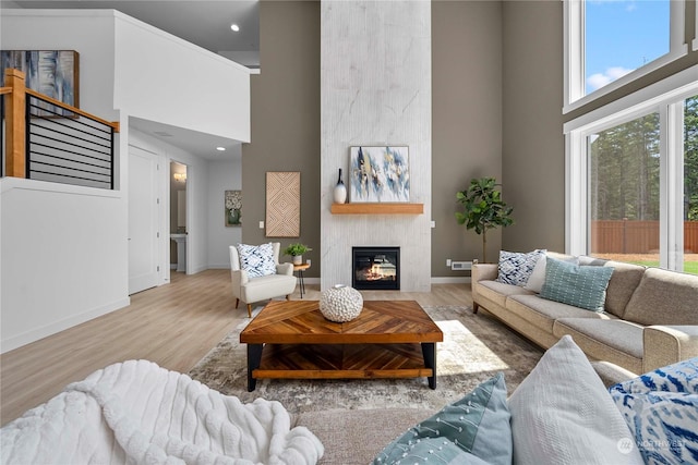 living room featuring hardwood / wood-style floors, a large fireplace, and a towering ceiling