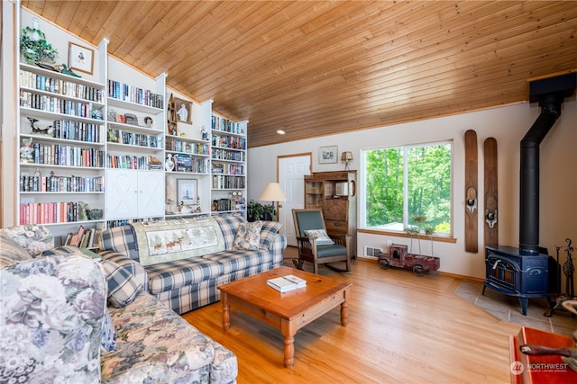 living room featuring wooden ceiling, lofted ceiling, a wood stove, and built in shelves