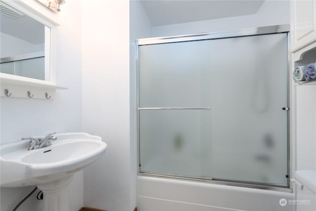 bathroom with combined bath / shower with glass door and toilet