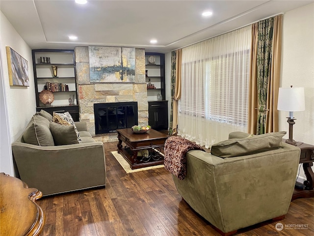 living room featuring dark hardwood / wood-style flooring, built in shelves, and a fireplace