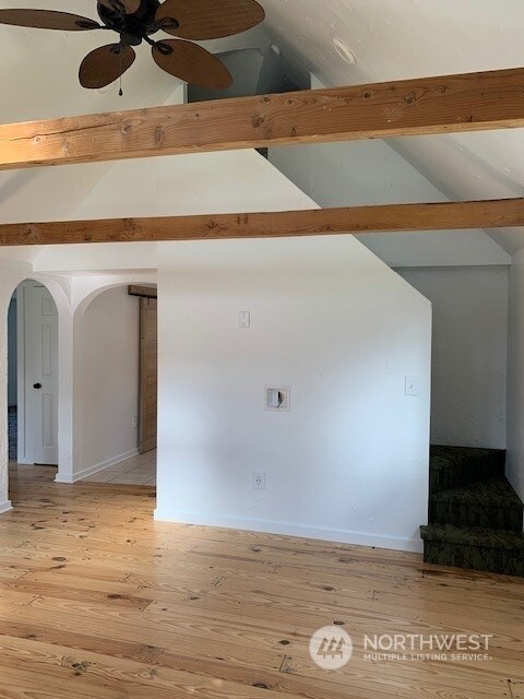 unfurnished room featuring ceiling fan, vaulted ceiling with beams, and light wood-type flooring