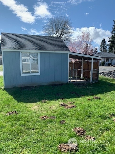 rear view of property featuring a lawn and an outdoor structure