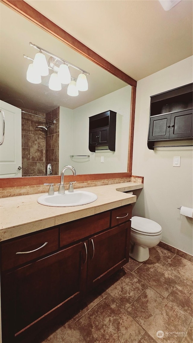 bathroom with a tile shower, vanity, and toilet