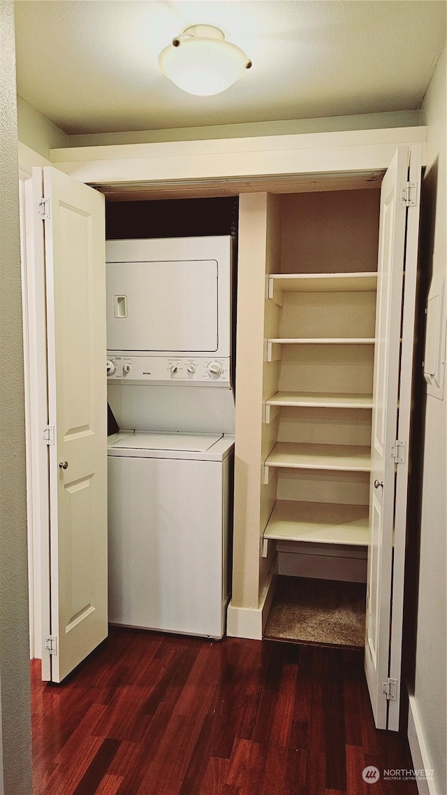 laundry area with stacked washer / dryer and dark hardwood / wood-style flooring