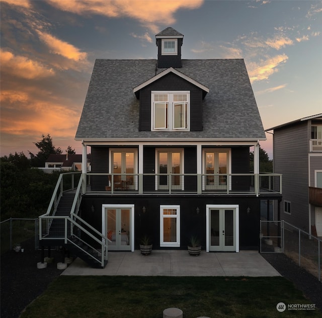 back house at dusk featuring a balcony, a patio area, and french doors