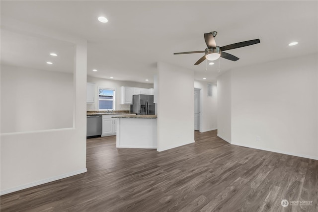 unfurnished living room featuring dark wood-type flooring and ceiling fan