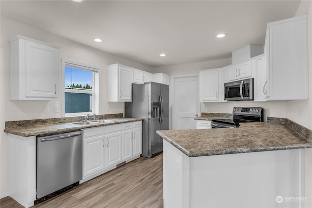 kitchen featuring sink, kitchen peninsula, white cabinets, and appliances with stainless steel finishes