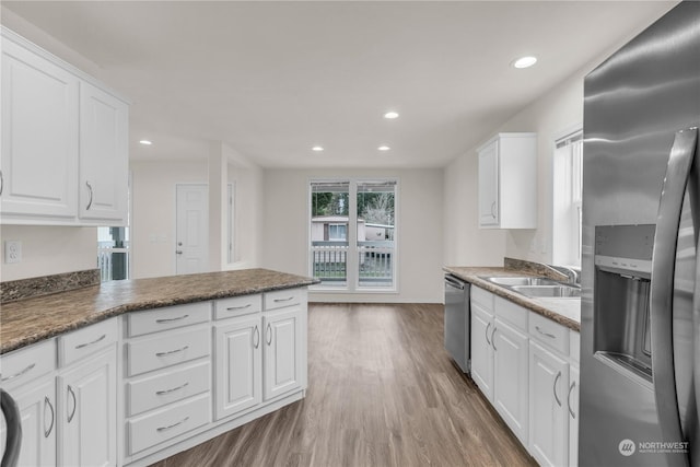 kitchen with sink, white cabinets, hardwood / wood-style flooring, kitchen peninsula, and stainless steel appliances