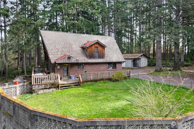 view of front of home featuring a front lawn, a wooden deck, and an outdoor structure