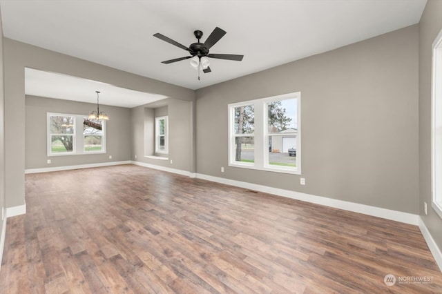 unfurnished room with ceiling fan with notable chandelier and wood-type flooring