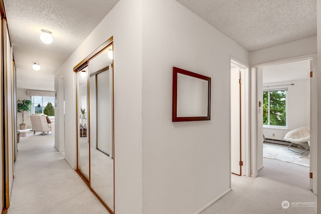 corridor featuring light colored carpet and a textured ceiling