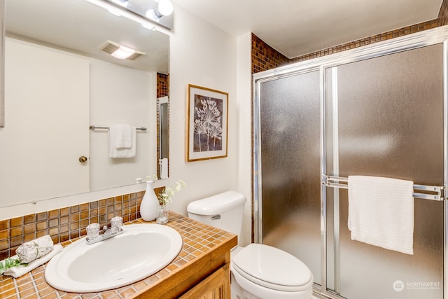 bathroom featuring walk in shower, tasteful backsplash, vanity, and toilet