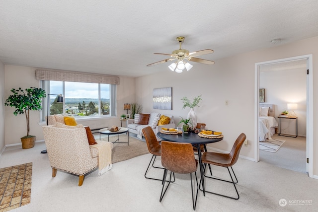 carpeted dining area featuring a textured ceiling and ceiling fan