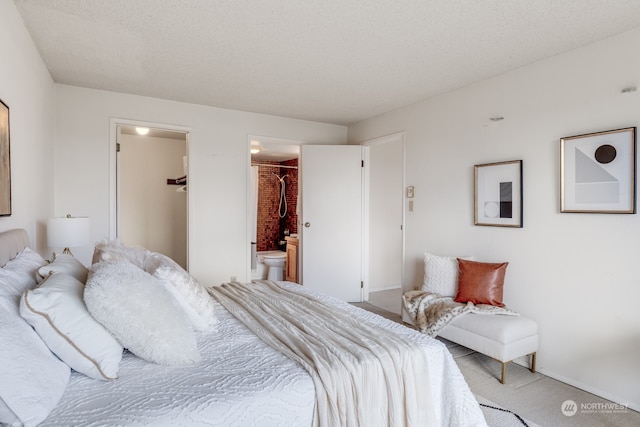 carpeted bedroom with a textured ceiling, connected bathroom, a closet, and a walk in closet