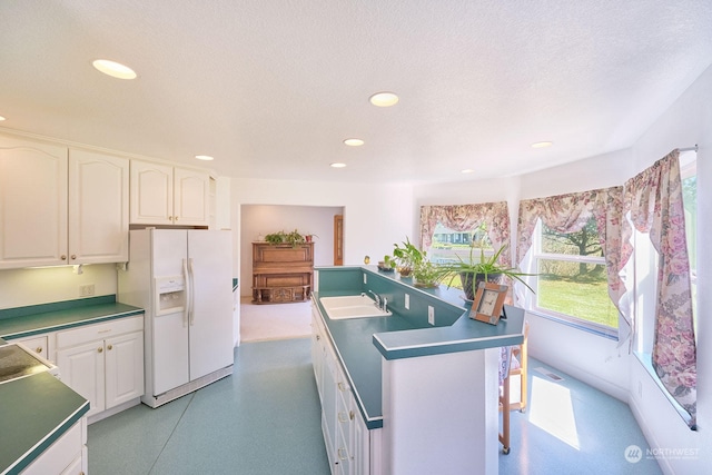 kitchen featuring white refrigerator with ice dispenser, white cabinets, and a textured ceiling