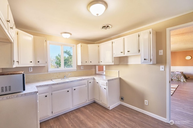 kitchen with light hardwood / wood-style flooring, sink, and white cabinetry