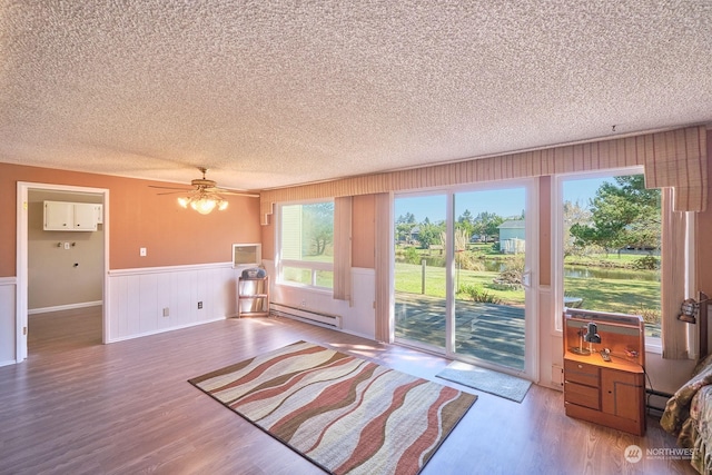 doorway to outside featuring ceiling fan, baseboard heating, hardwood / wood-style flooring, and a textured ceiling