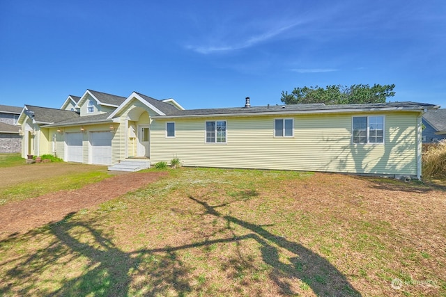 rear view of property featuring a yard and a garage