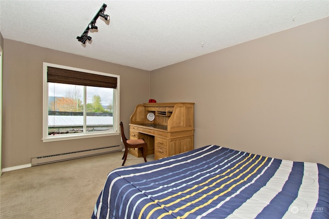 carpeted bedroom with a baseboard heating unit, a textured ceiling, and track lighting