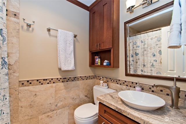 bathroom featuring tile walls, backsplash, toilet, vanity, and crown molding