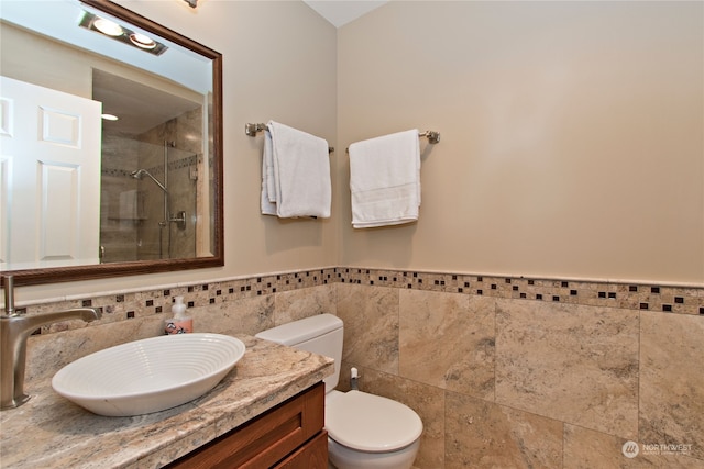 bathroom featuring toilet, vanity, a tile shower, and tasteful backsplash