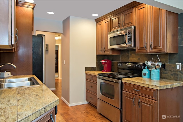 kitchen featuring appliances with stainless steel finishes, light hardwood / wood-style floors, tasteful backsplash, and sink