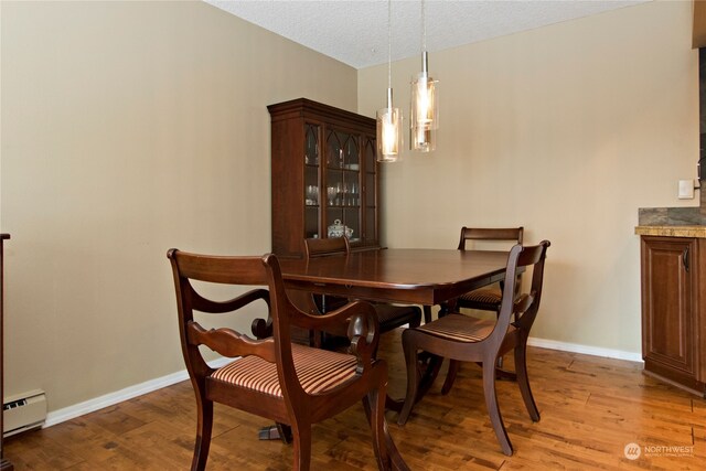 dining room with a baseboard radiator, a textured ceiling, and light hardwood / wood-style floors