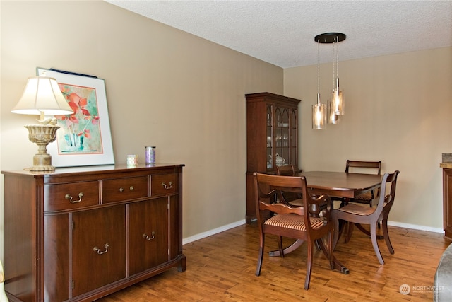 dining area with a textured ceiling and light wood-type flooring