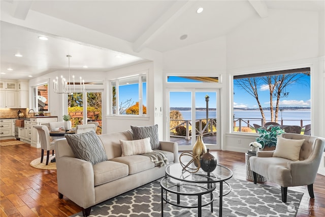 living room featuring a water view, dark wood-type flooring, lofted ceiling with beams, and a chandelier