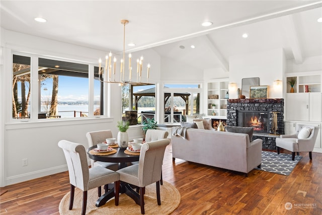 dining area with built in features, a water view, vaulted ceiling with beams, dark wood-type flooring, and a chandelier