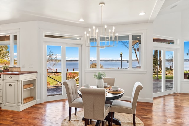 dining area with light hardwood / wood-style flooring, a water view, and an inviting chandelier