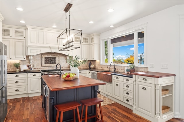 kitchen featuring a center island with sink, tasteful backsplash, dark wood-type flooring, sink, and pendant lighting