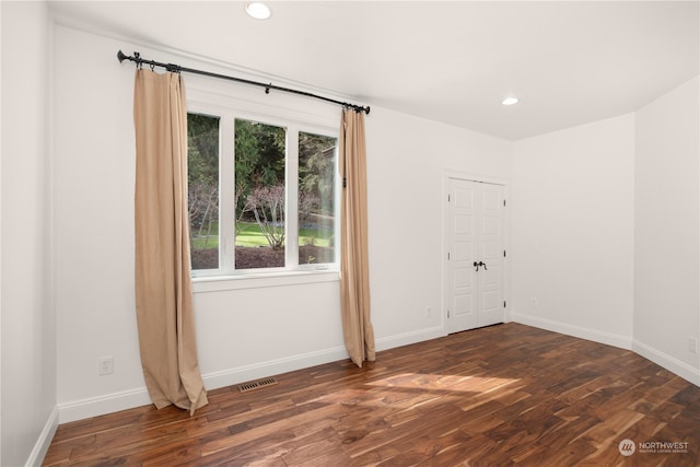 unfurnished room with plenty of natural light and dark wood-type flooring