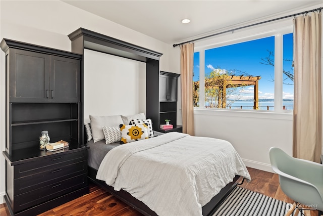 bedroom with a water view and dark hardwood / wood-style floors