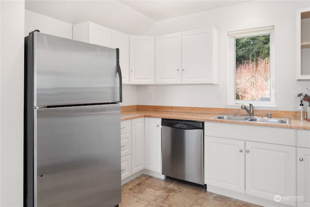 kitchen featuring appliances with stainless steel finishes, sink, light tile floors, and white cabinets