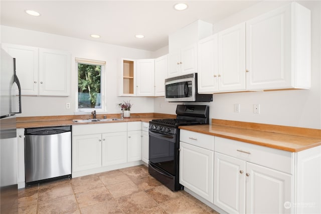 kitchen with white cabinets, sink, appliances with stainless steel finishes, and light tile flooring