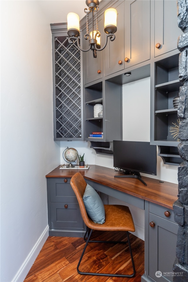 home office featuring a chandelier, built in desk, and dark wood-type flooring