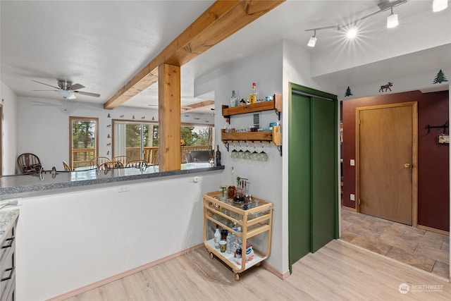 kitchen with beamed ceiling, stone counters, rail lighting, ceiling fan, and light tile floors