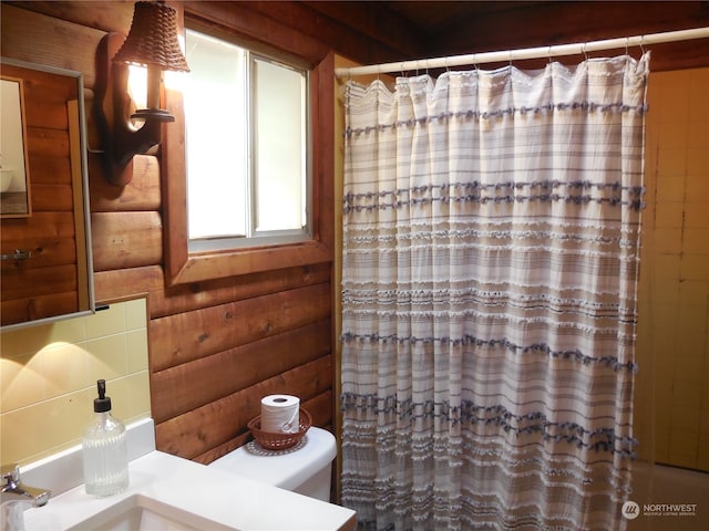 bathroom with rustic walls, toilet, and sink