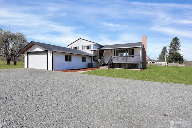 view of front of property featuring an outdoor structure, a garage, a front lawn, central AC unit, and covered porch