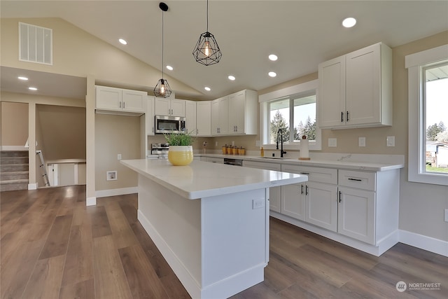 kitchen featuring white cabinets, hanging light fixtures, a kitchen island, and dark wood-type flooring