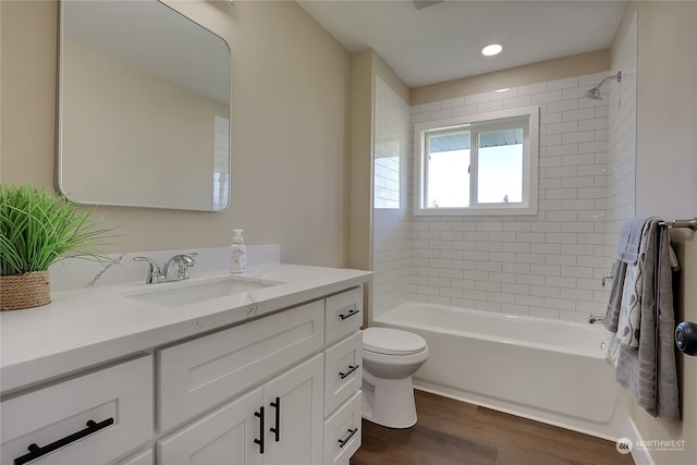 full bathroom with hardwood / wood-style flooring, tiled shower / bath, toilet, and vanity