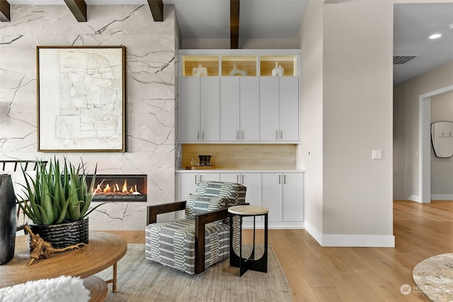 sitting room with light hardwood / wood-style flooring, beam ceiling, and a high end fireplace