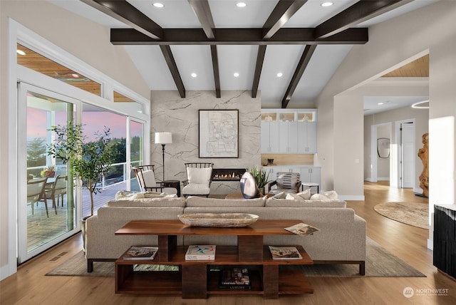 living room with vaulted ceiling with beams and light hardwood / wood-style floors