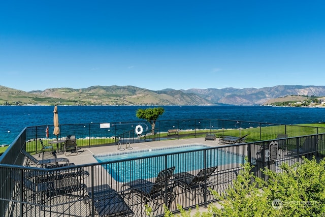 view of swimming pool with a patio area and a water and mountain view